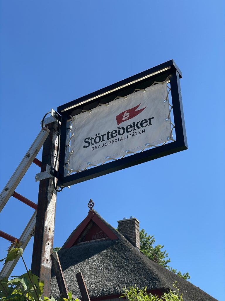 Störtebeker-Schild am Mast vor dem Reetdach